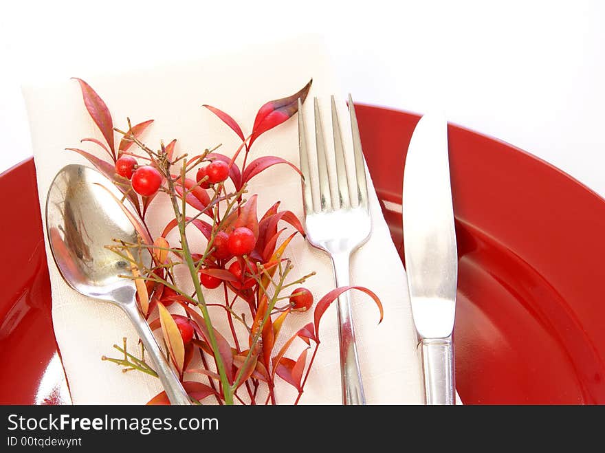 Elegant table setting in red and white, with fresh sprigs of leaves and berries. Elegant table setting in red and white, with fresh sprigs of leaves and berries