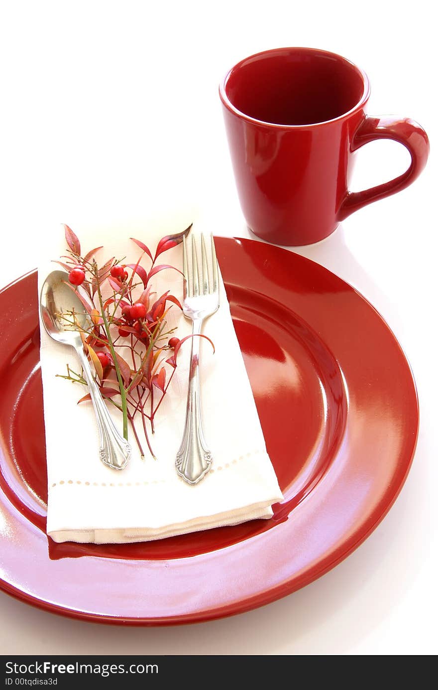 Elegant table setting in red and white, with fresh sprigs of leaves and berries. Elegant table setting in red and white, with fresh sprigs of leaves and berries