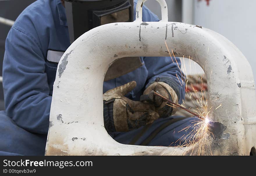 A welder working at shipyard during day. A welder working at shipyard during day