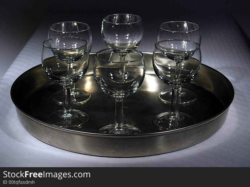 Six glasses on a plate in spotlight, using three spots to bring the light directly on to the plate darkening the background. Six glasses on a plate in spotlight, using three spots to bring the light directly on to the plate darkening the background