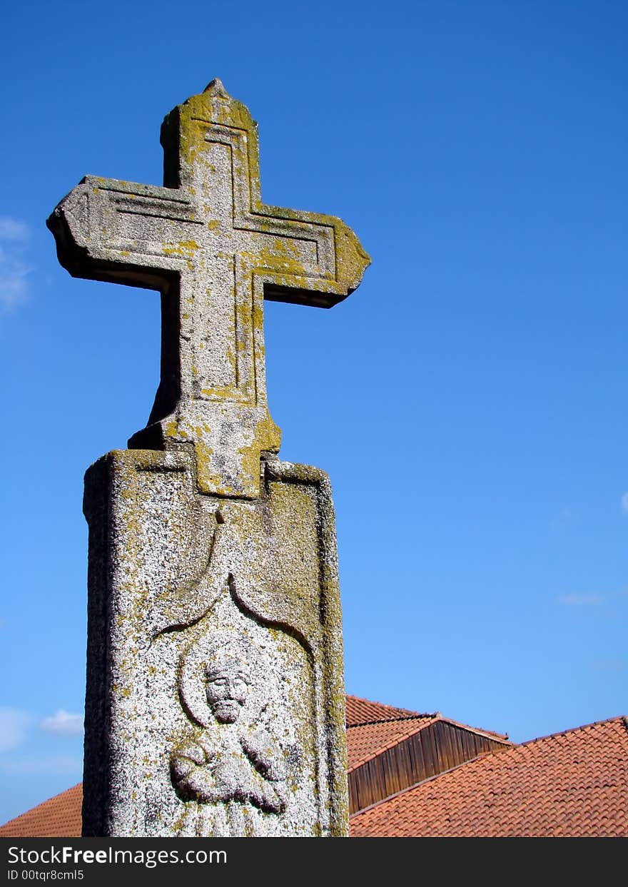 Stone cross landmark over roofs in a blue sky