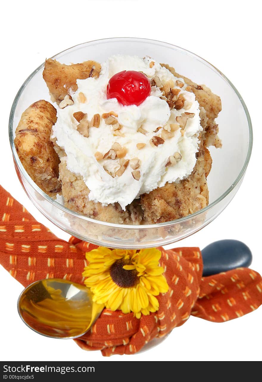 Homemade cinnamon roll bread pudding in glass with spoon and flower over white.