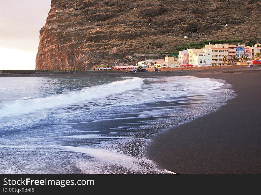 Volcanic beach of La Palma, village in the water reflection of Atlantic ocean with long surf. Volcanic beach of La Palma, village in the water reflection of Atlantic ocean with long surf