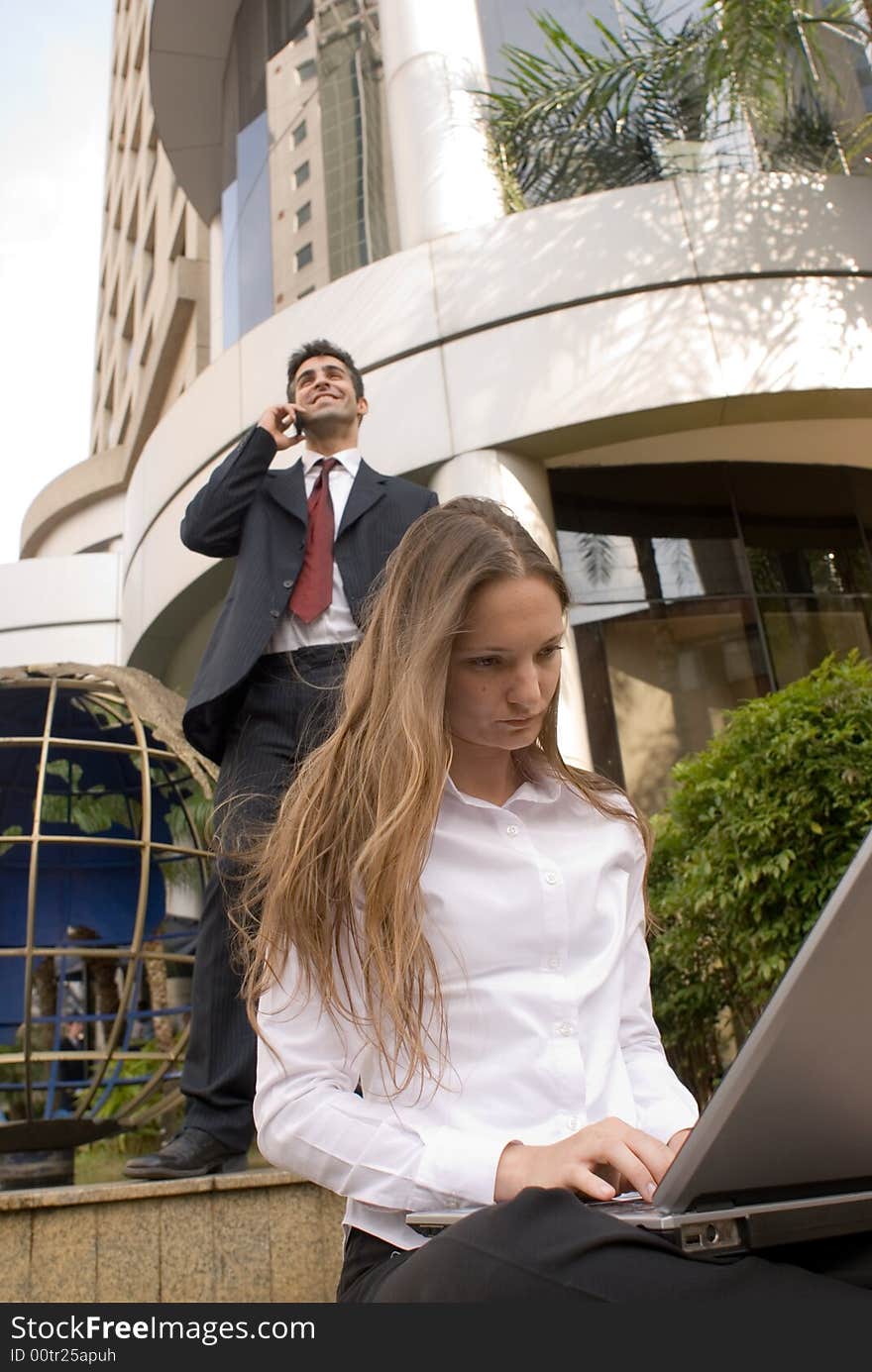 Male and female business people working on a laptop and on phone. Male and female business people working on a laptop and on phone