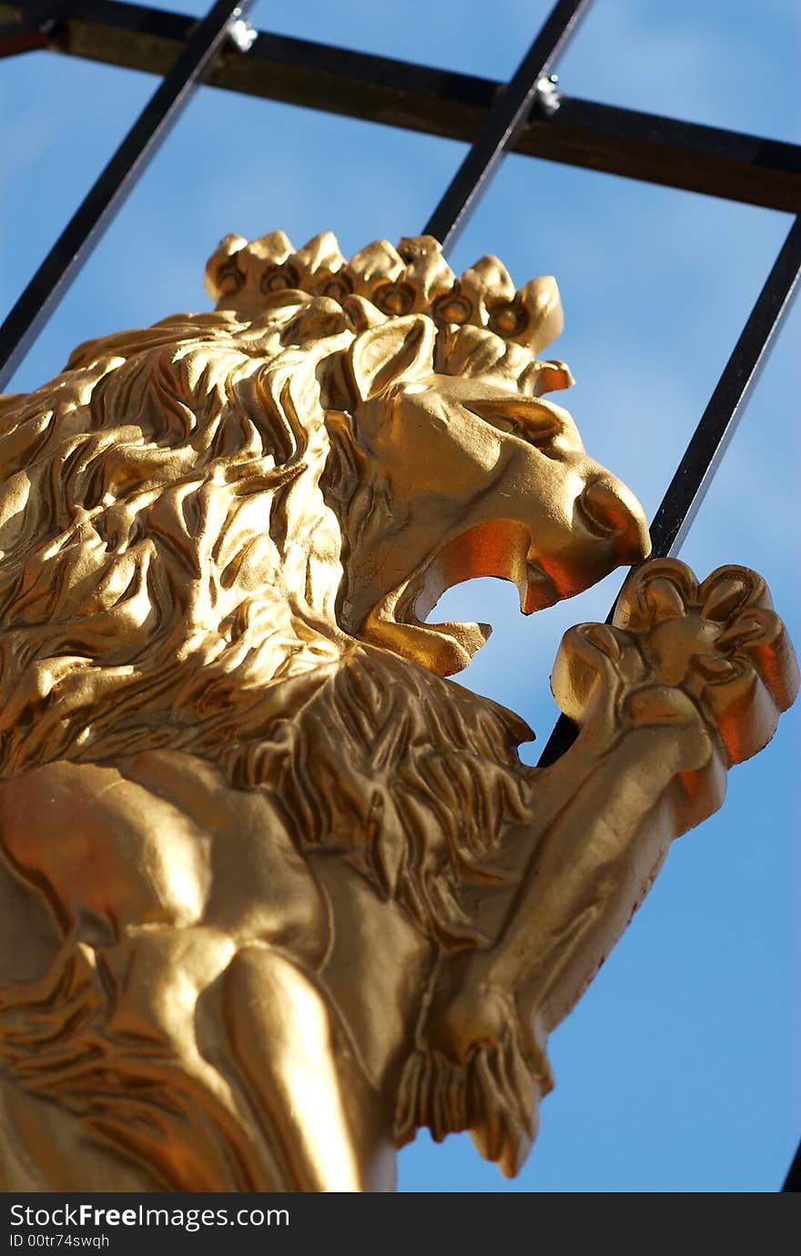 A golden lion on a cast iron gate at the entrance to a home.