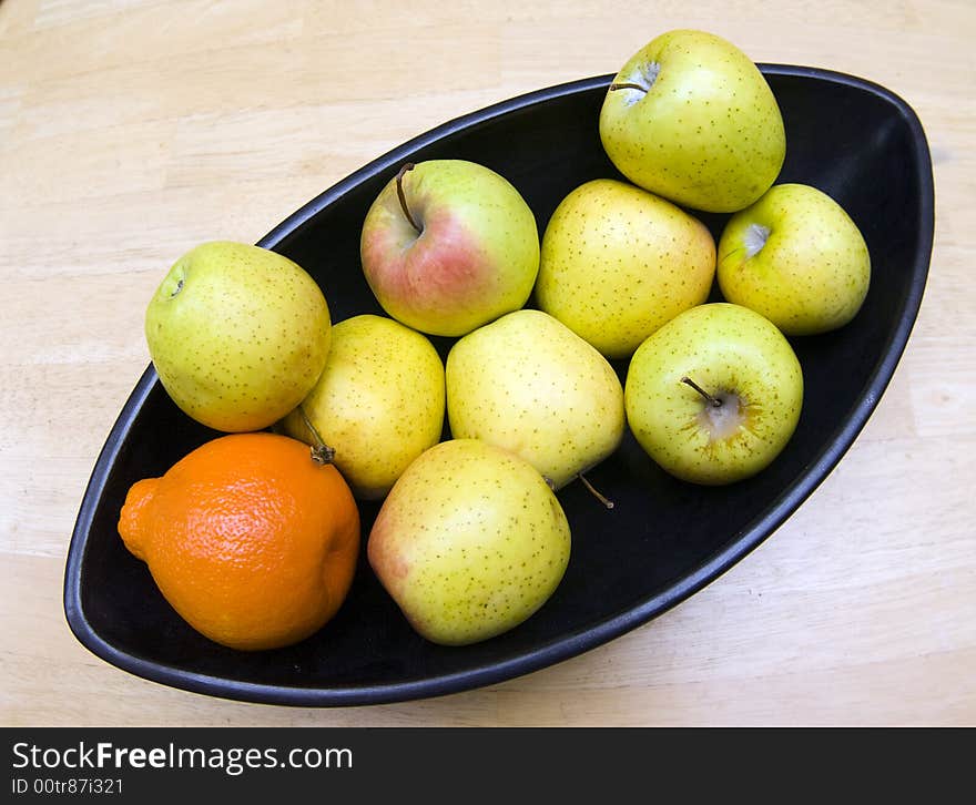 Black Japanese vase with apples and tangerine served at wooden table