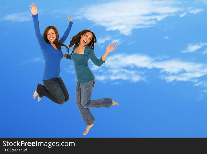 Two girls having fun by throwing themselves up in the blue sky with silly expression. Two girls having fun by throwing themselves up in the blue sky with silly expression