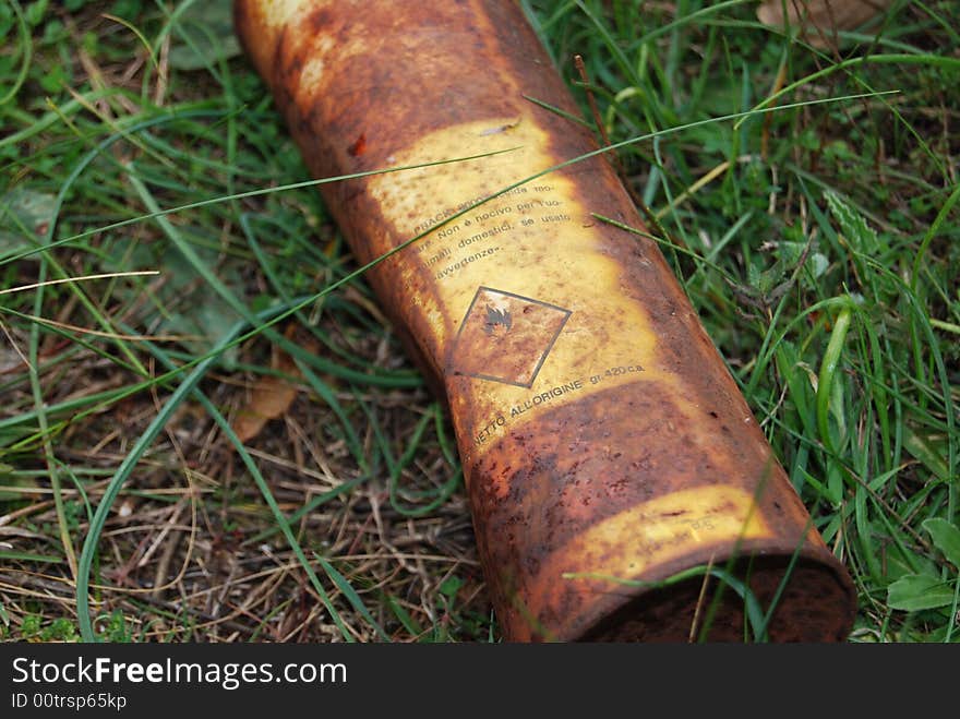 A rusted metal tin can thrown in a green field. A rusted metal tin can thrown in a green field