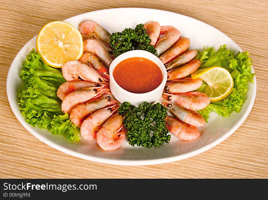 Shrimps with lemon, sauce and lettuce on table