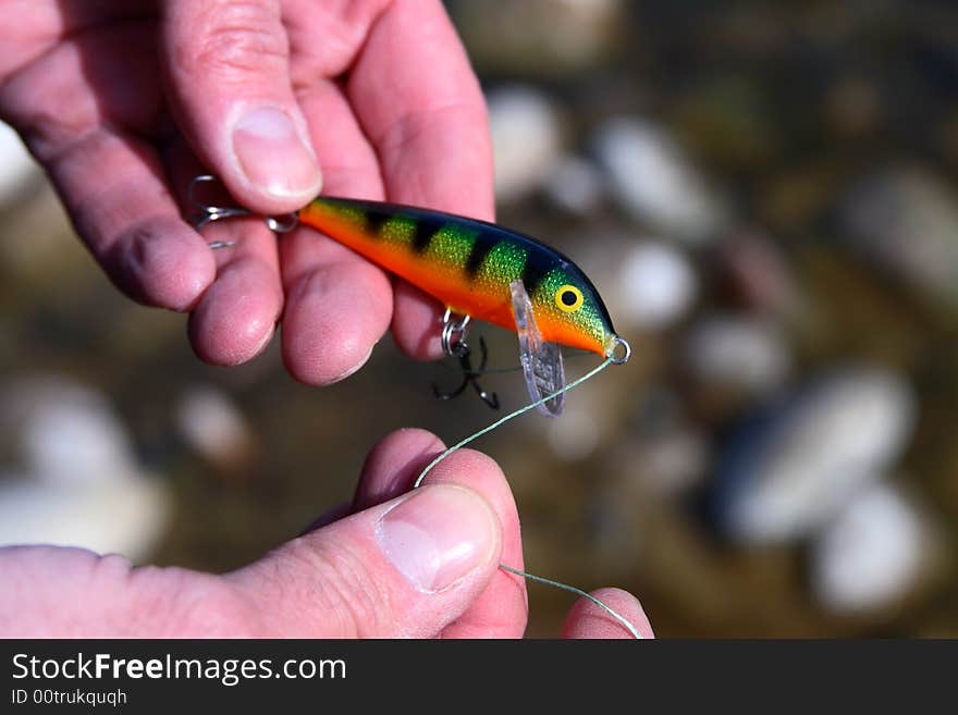 An angler tying on a fishing lure before hitting the river