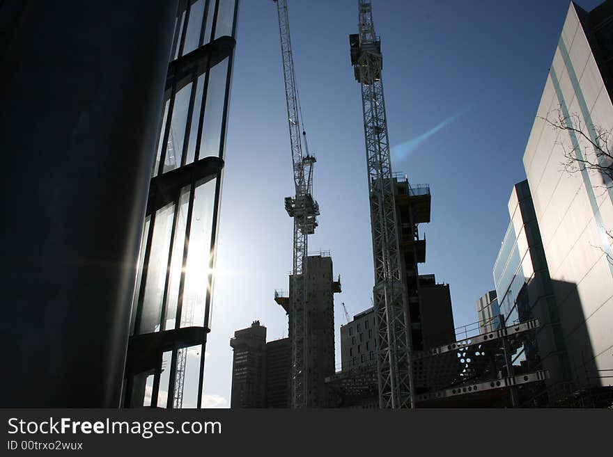 In the picture are represented some scaffoldings and cranes in a very new and modern urban environment. In the picture are represented some scaffoldings and cranes in a very new and modern urban environment