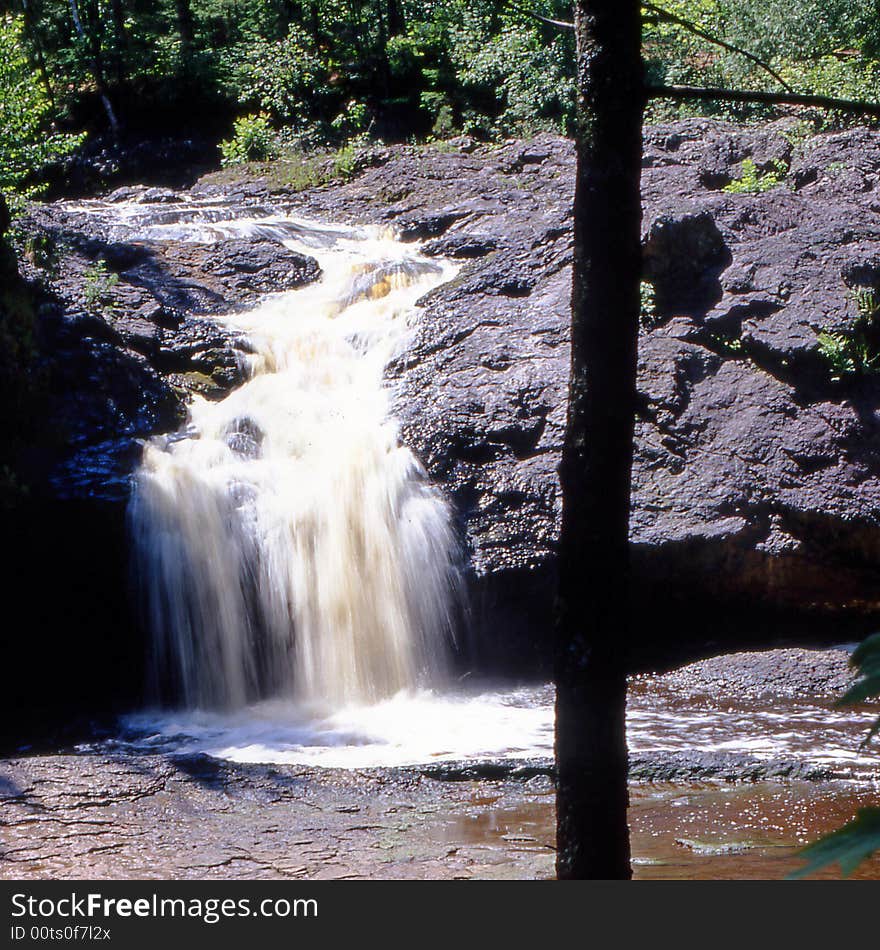 grey gray bluffs and blurred white water falls over Amnicon Falls the Upper Falls at Amnicon Falls State Park over bluff of basalt rock part of niagara escarpment which stretches to canada and is in a park that has four waterfalls in northern forests of wisconsin in the united states of america showing a wild wilderness of pure power of the northwood environment of thick heavy trees. grey gray bluffs and blurred white water falls over Amnicon Falls the Upper Falls at Amnicon Falls State Park over bluff of basalt rock part of niagara escarpment which stretches to canada and is in a park that has four waterfalls in northern forests of wisconsin in the united states of america showing a wild wilderness of pure power of the northwood environment of thick heavy trees