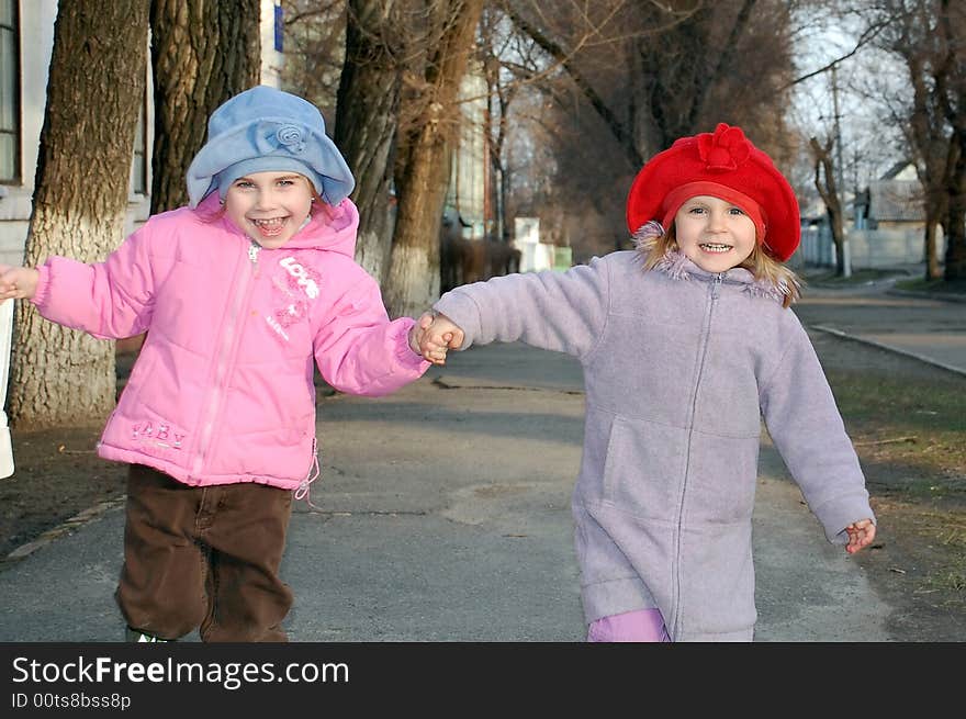 Merry running children holding hands and wearing hats. Merry running children holding hands and wearing hats