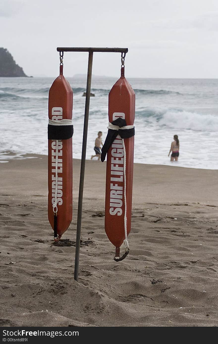 Surf lifeguard belts hanging with children playing in surf.