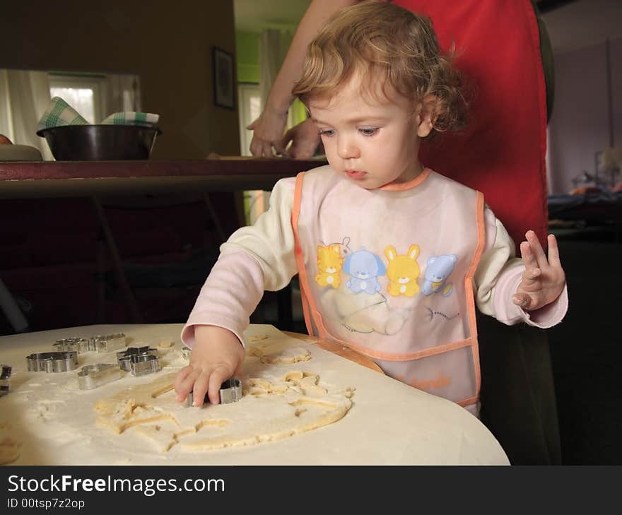 A child is helping mom to prepare the cookies. A child is helping mom to prepare the cookies.