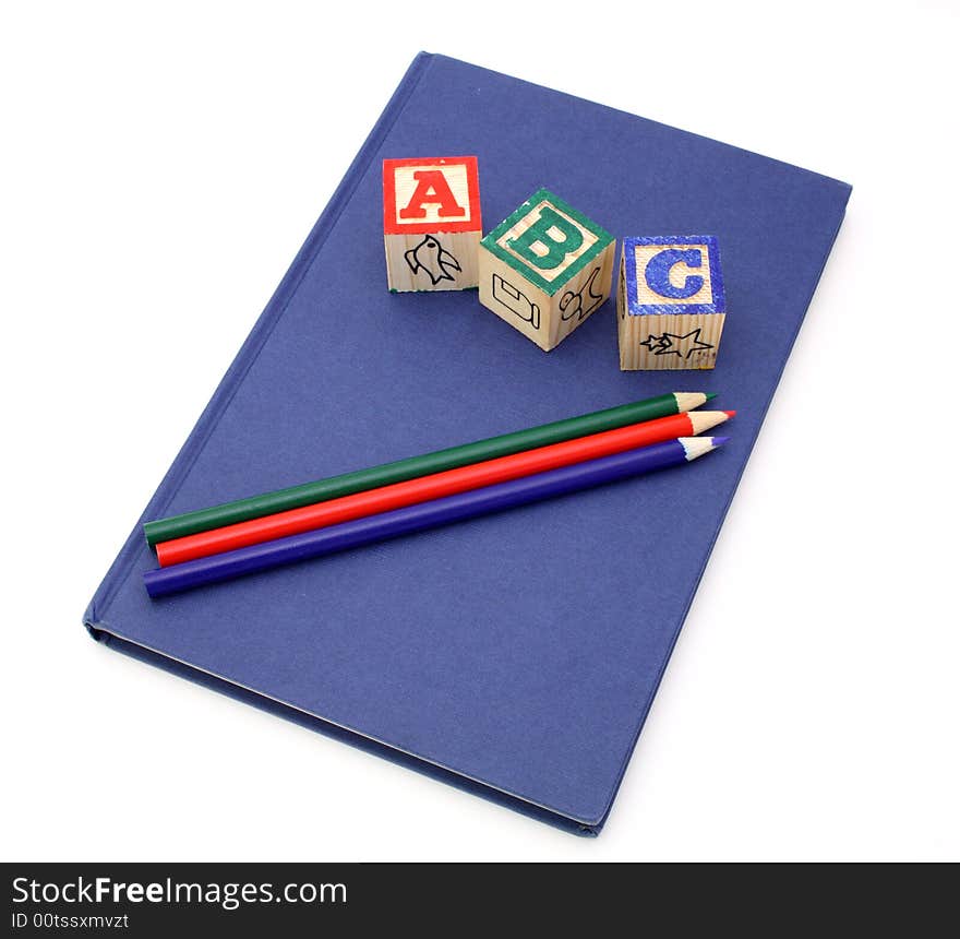 Alphabet blocks and colored pencils over a blue notebook. Alphabet blocks and colored pencils over a blue notebook