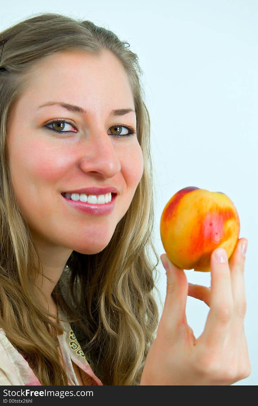 Smiling attractive young lady with a fresh colorful peach. Smiling attractive young lady with a fresh colorful peach