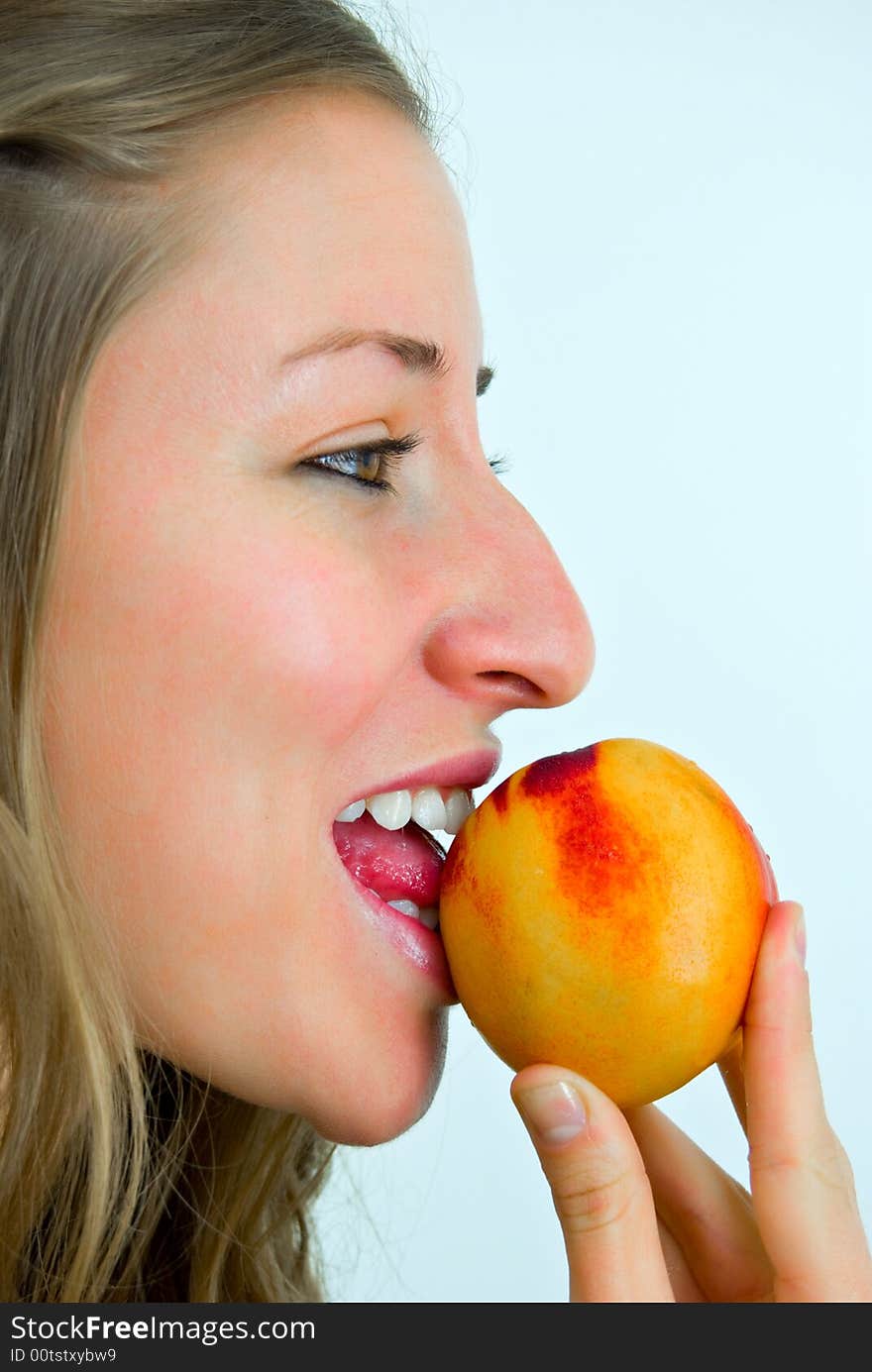 Smiling girl eating a peach