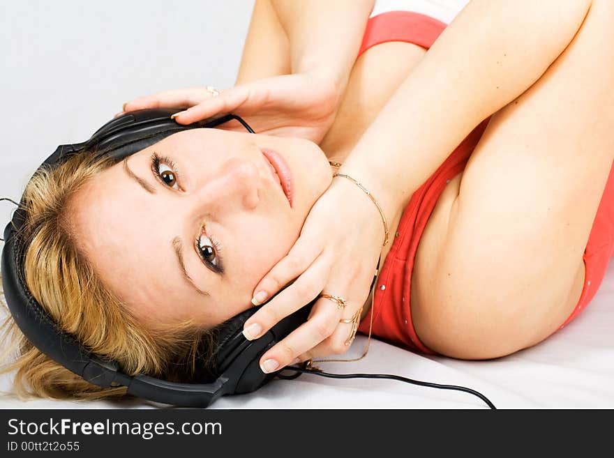 Lying woman with headphones listening music