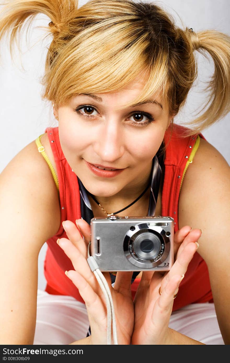 Young girl clothed in T-shirt holding digital camera