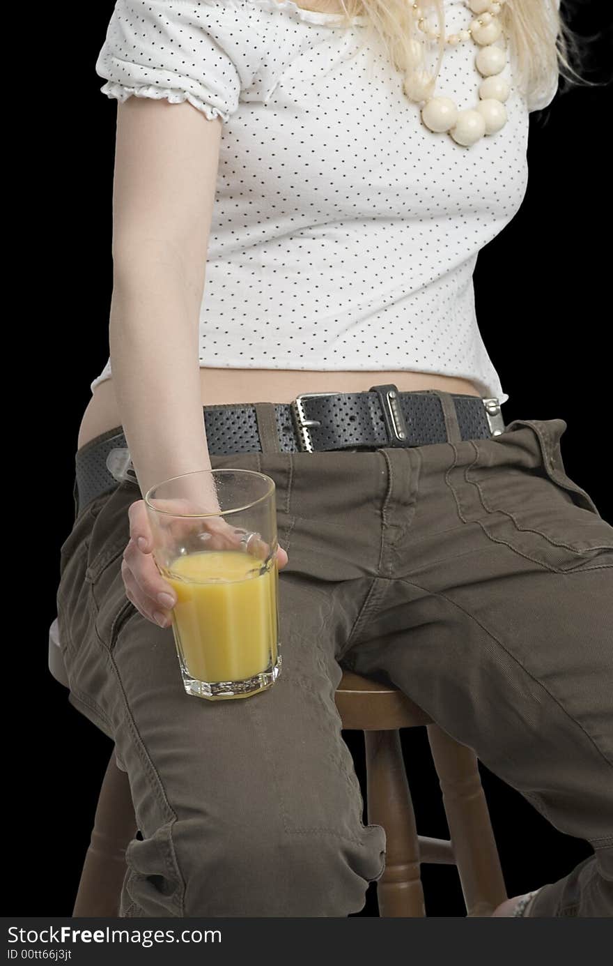 A glass of juice in the hand of young girl on the black background