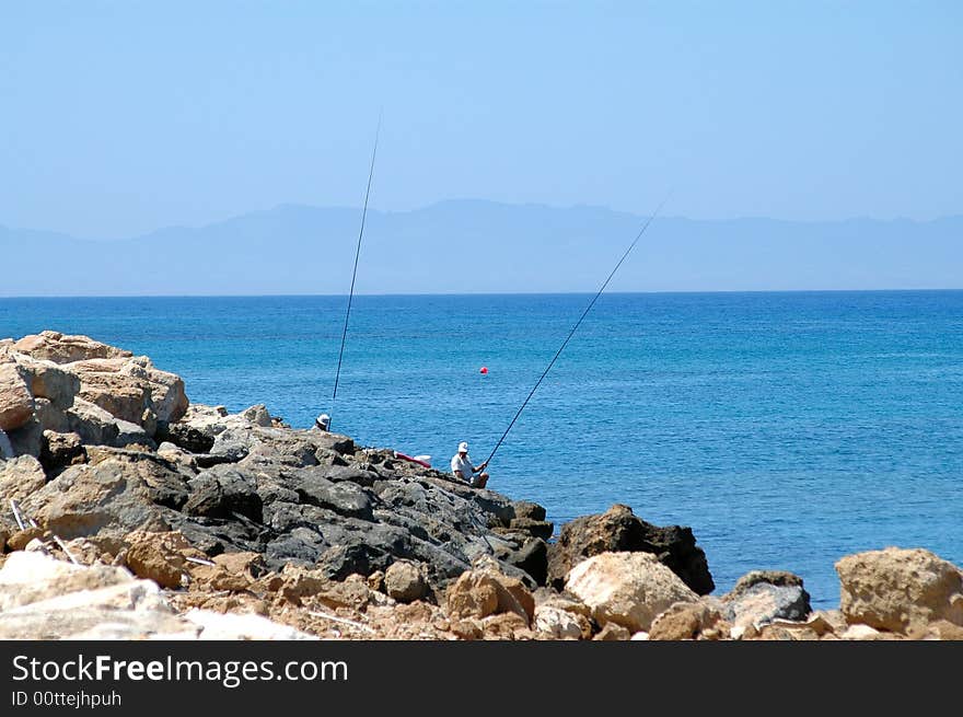 Sea costline two people fishing in action