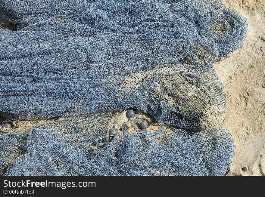 A blue industrial fishing net laying on the beach. A blue industrial fishing net laying on the beach.