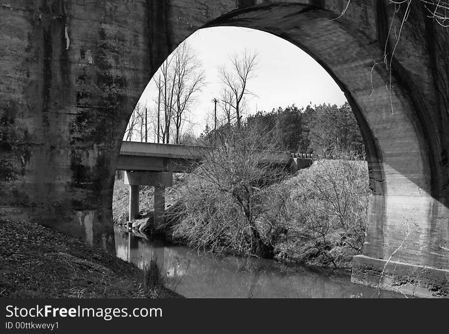 A black and white picture of a the underside of a bridge. A black and white picture of a the underside of a bridge