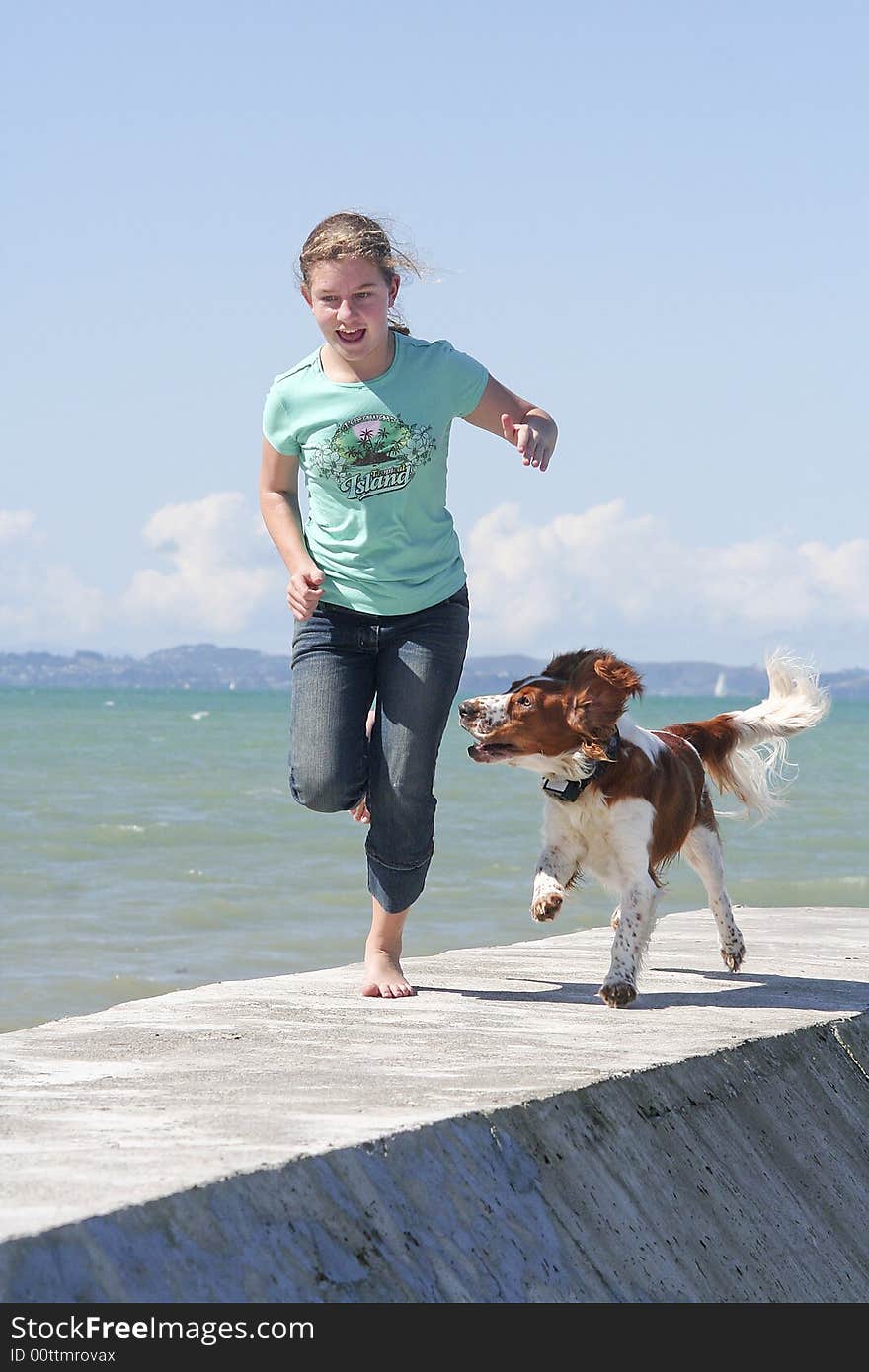 Teenage girl running with her dog at the beach. Teenage girl running with her dog at the beach