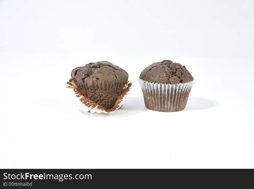 Two chocolate chip muffins in muffin cases with one muffin exposed. Two chocolate chip muffins in muffin cases with one muffin exposed