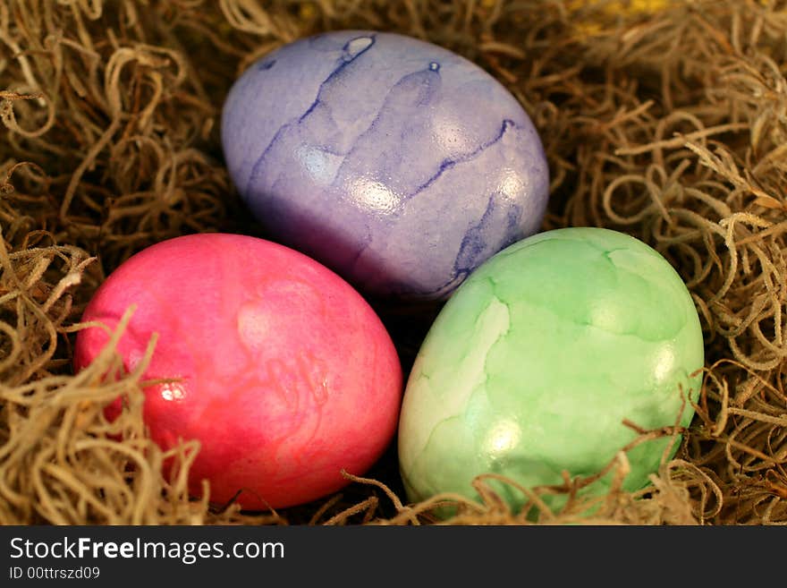 Three colorful pastel Easter Eggs in a basket.