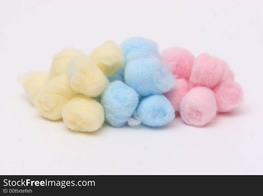 Yellow, blue and pink hygienic cotton balls isolated on a white background