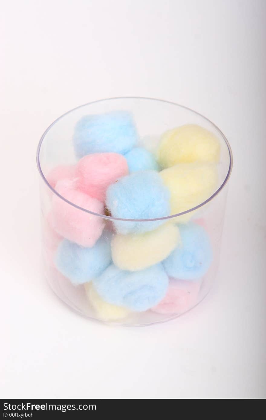 Blue and pink hygienic cotton balls in a glass canister isolated on a white background