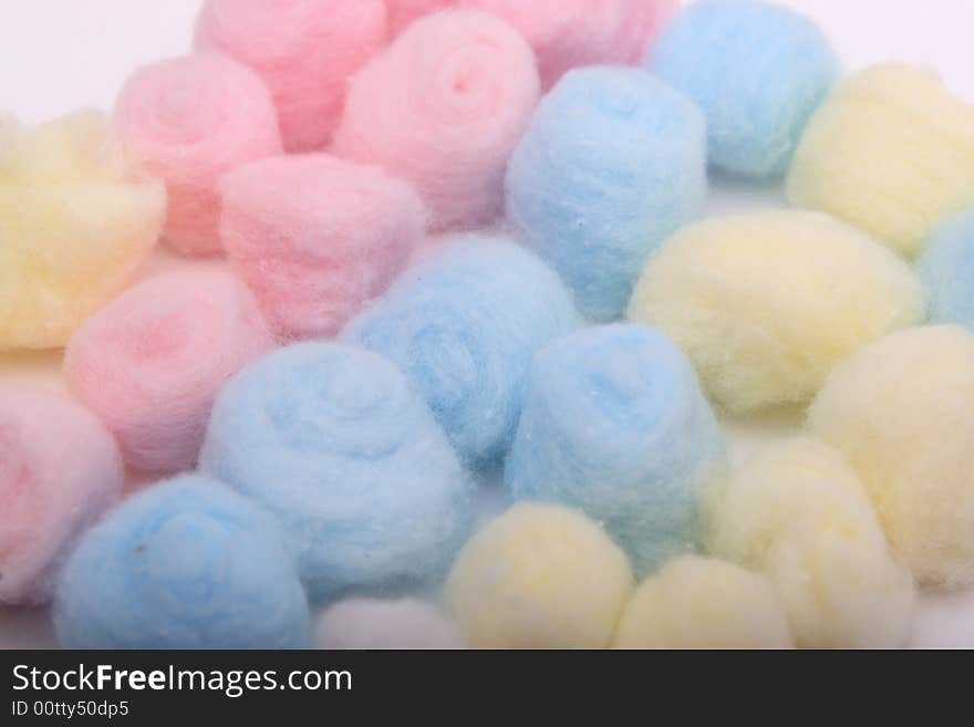 Yellow, blue and pink hygienic cotton balls in rows isolated on a white background