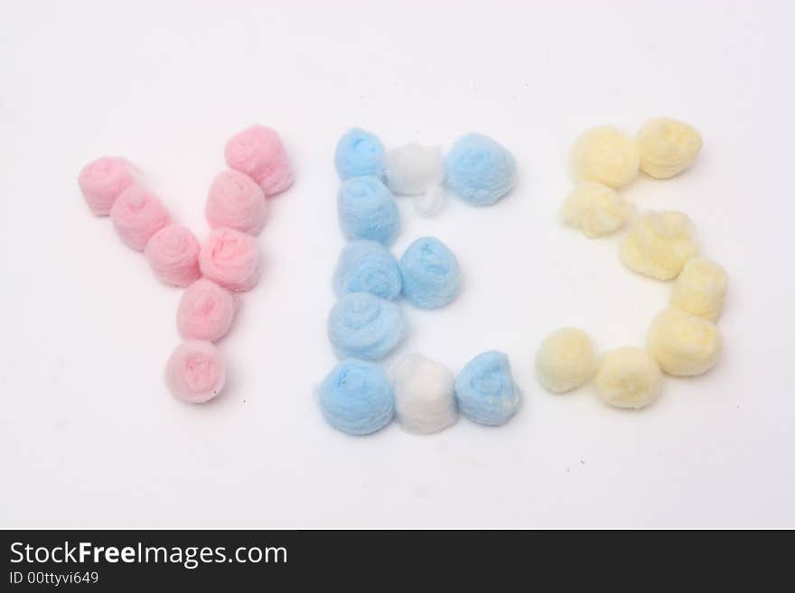 Word yes with blue, yellow and pink hygienic cotton balls isolated on a white background. Word yes with blue, yellow and pink hygienic cotton balls isolated on a white background