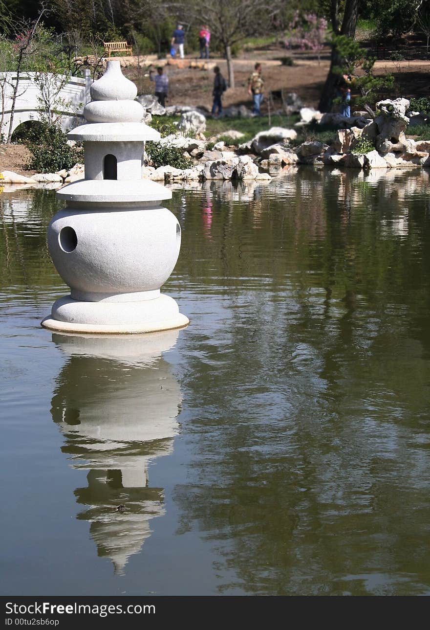 A statue set in a lake at a Chinese Garden.