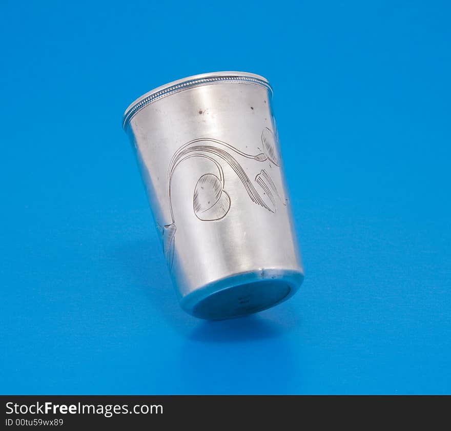 Vintage silver small drinking vessel with engraving over blue background