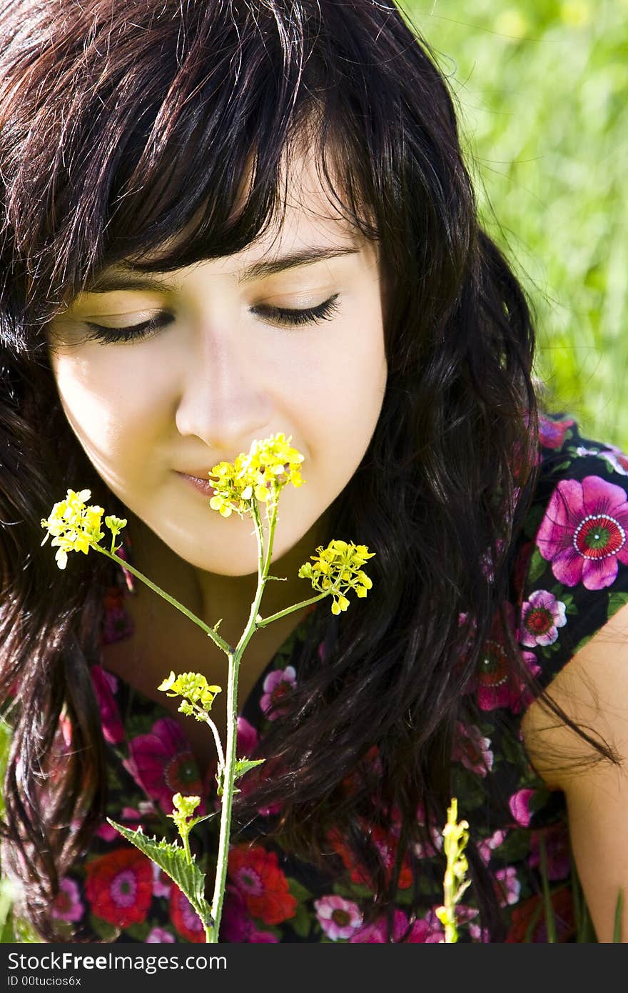 Young woman smelling yellow flower, green background