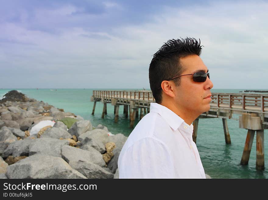 Man standing on the rocks near a pier at the beach. Man standing on the rocks near a pier at the beach.