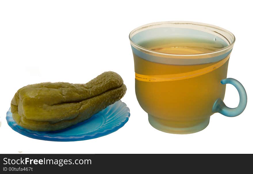 Glass mug with tea and a cucumber on a plate on a white background. Photo.