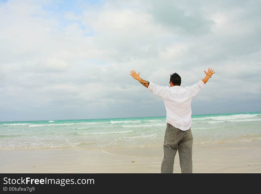 Man with arms extended facing the ocean. Man with arms extended facing the ocean