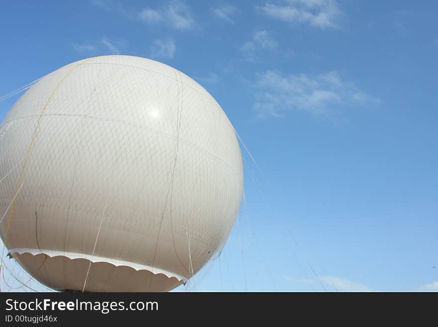 White Balloon On Blue Sky being held down by ropes.