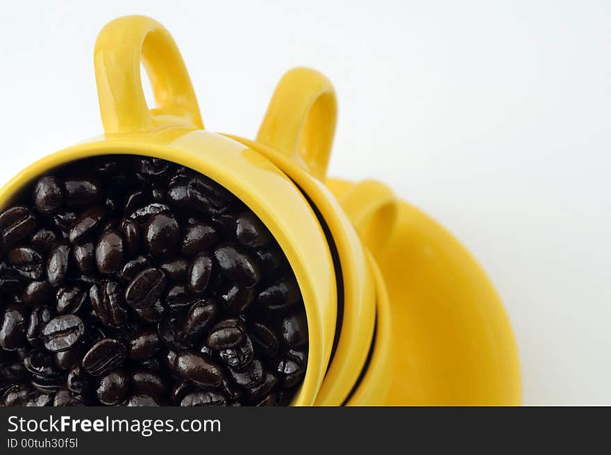 Three yellow cups with coffe beans isolated on white