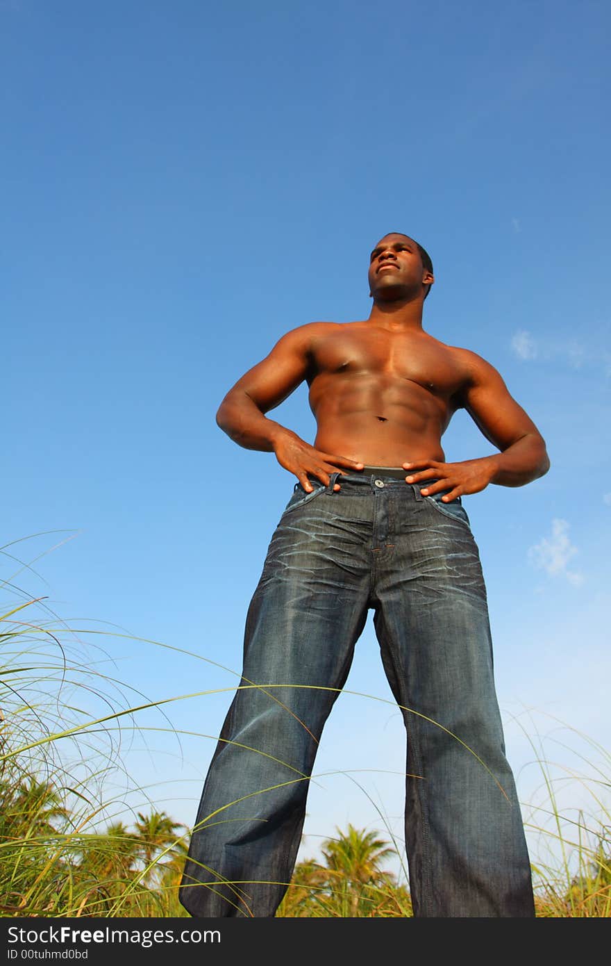 Tall bodybuilder wearing jeans and standing outside.