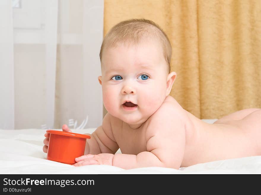 Small baby with toy on bed at home