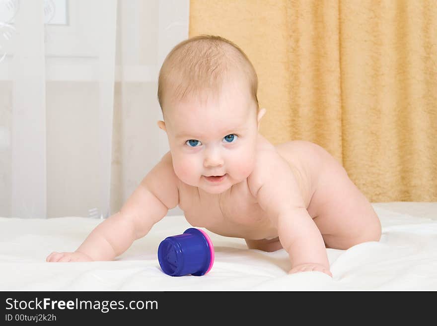 Small baby with toy on bed at home