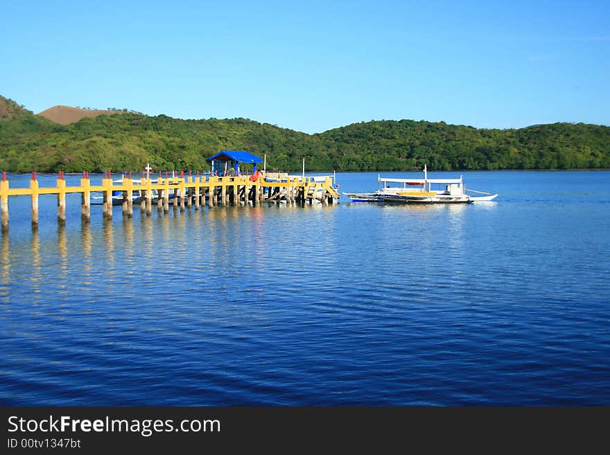 A pier from a resort leading to a boat. A pier from a resort leading to a boat