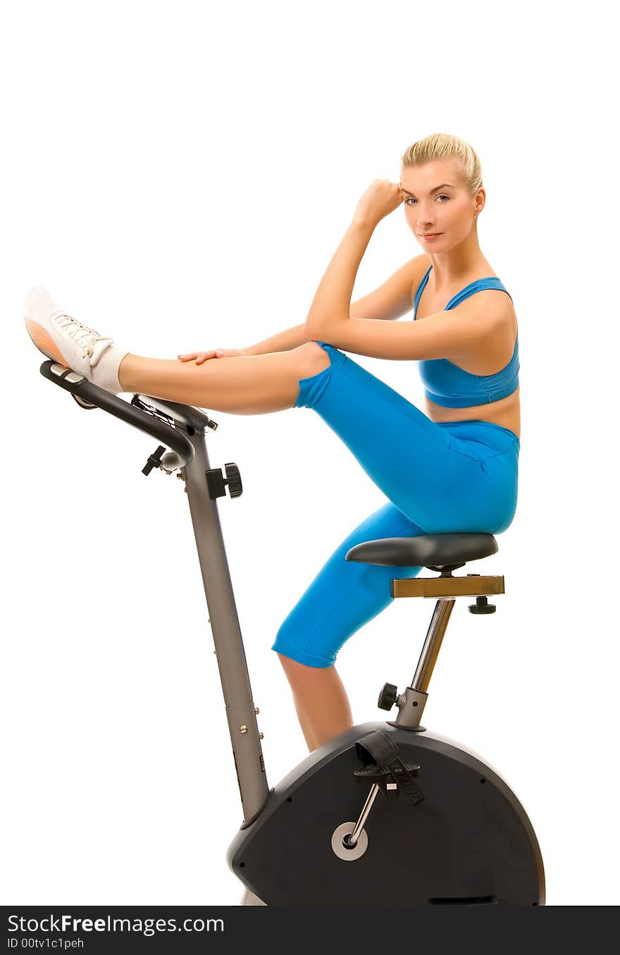 Beautiful young woman on exercise bicycle over white background