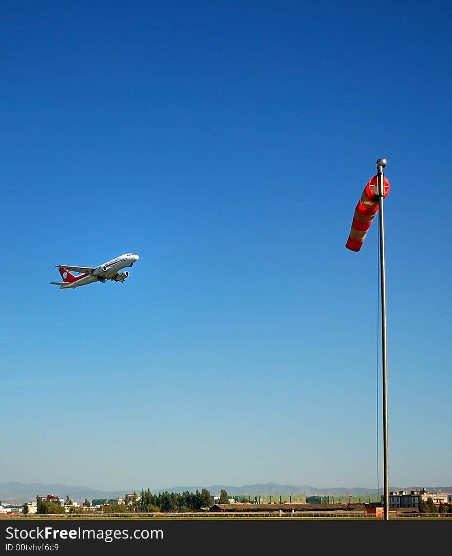 The plane was taking off at the airport and the wind indicator. The plane was taking off at the airport and the wind indicator