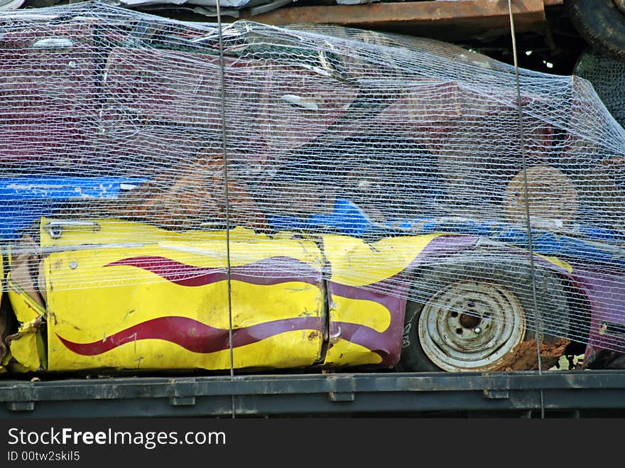 These vehicles have been scrapped as they are strapped and netted on the back of this trailer. The racing flames have been retired and were salvaged, crushed and on the way to be recycled. These vehicles have been scrapped as they are strapped and netted on the back of this trailer. The racing flames have been retired and were salvaged, crushed and on the way to be recycled.